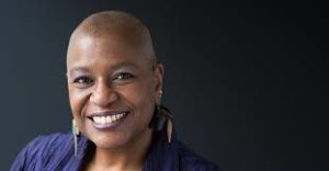 Rev. Dr. Velda Love black woman smiling on dark background.