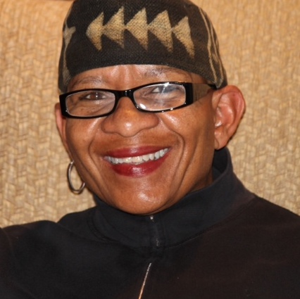 A person with red lipstick wearing black glasses and smiling..